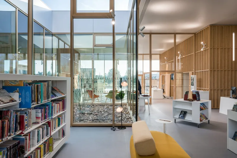 Library space with floor-to-ceiling glazing and timber-framed dividers under a skylight