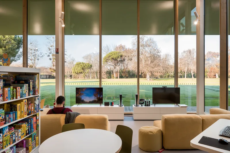 Reading area with full-height windows overlooking a park and bare trees