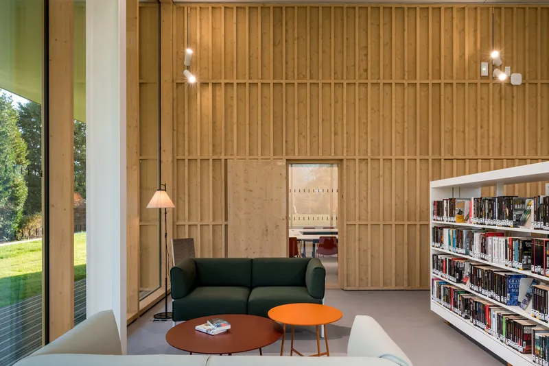 Reading area with vertical timber batten wall and a green sofa beneath pendant lighting