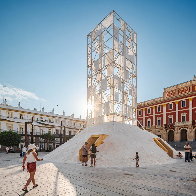 Openwork timber tower rising from a white salt pyramid as visitors walk across the plaza