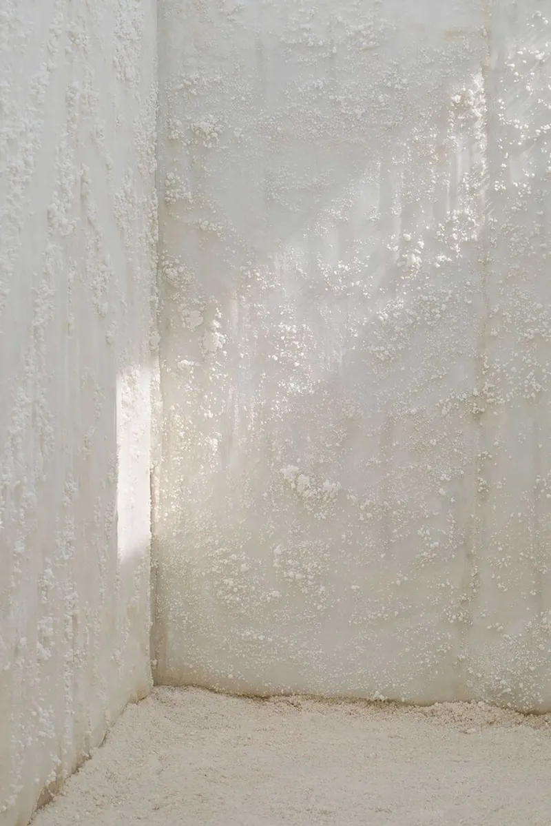 Corner detail of salt-crusted white plaster walls meeting at the floor with soft natural light