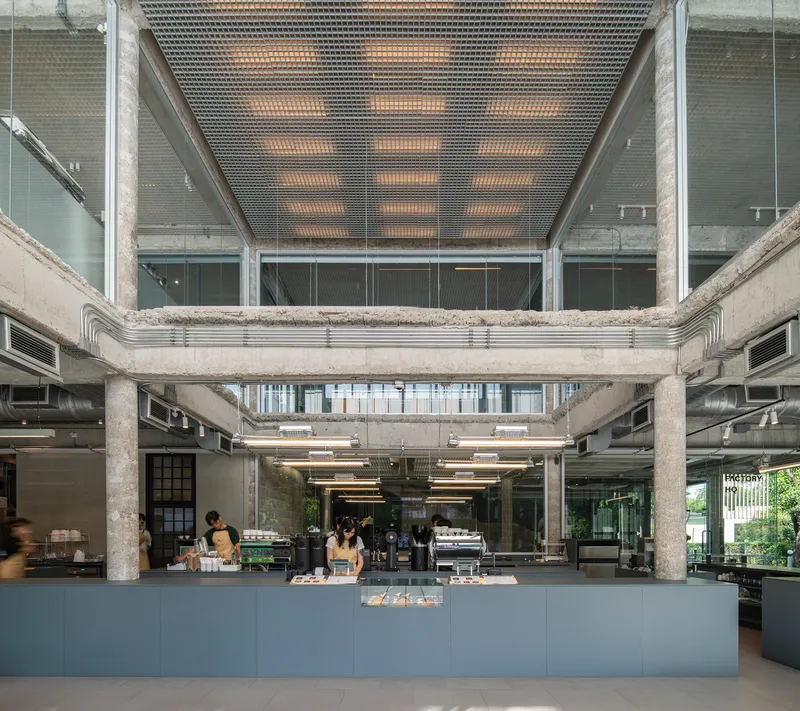 Double-height interior showing perforated metal ceiling panels above a central service counter with customers