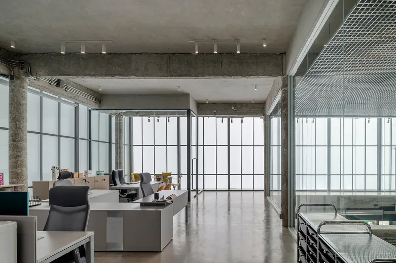 Upper level workspace with gridded translucent glazing and polished concrete floors under exposed ceiling