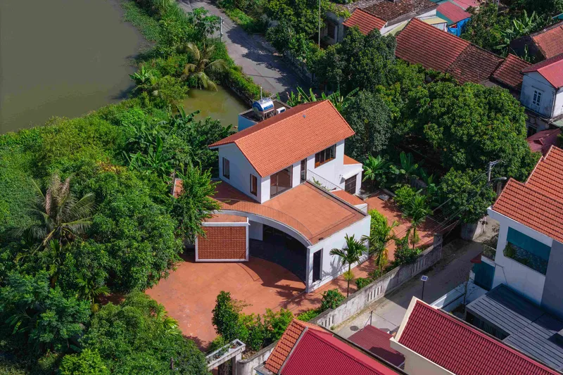 Aerial view of the compound showing terracotta tile roofs and paved courtyard among dense foliage