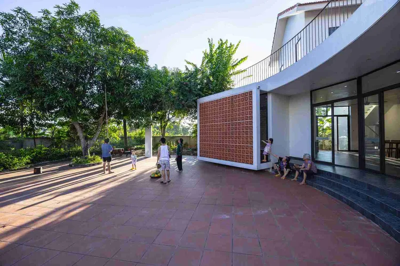 Covered terrace with perforated brick screen casting long shadows across terracotta tile flooring at afternoon