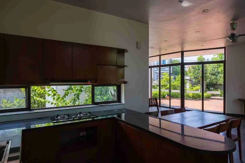 Kitchen with dark timber cabinetry and horizontal window beneath upper cabinets framing garden views