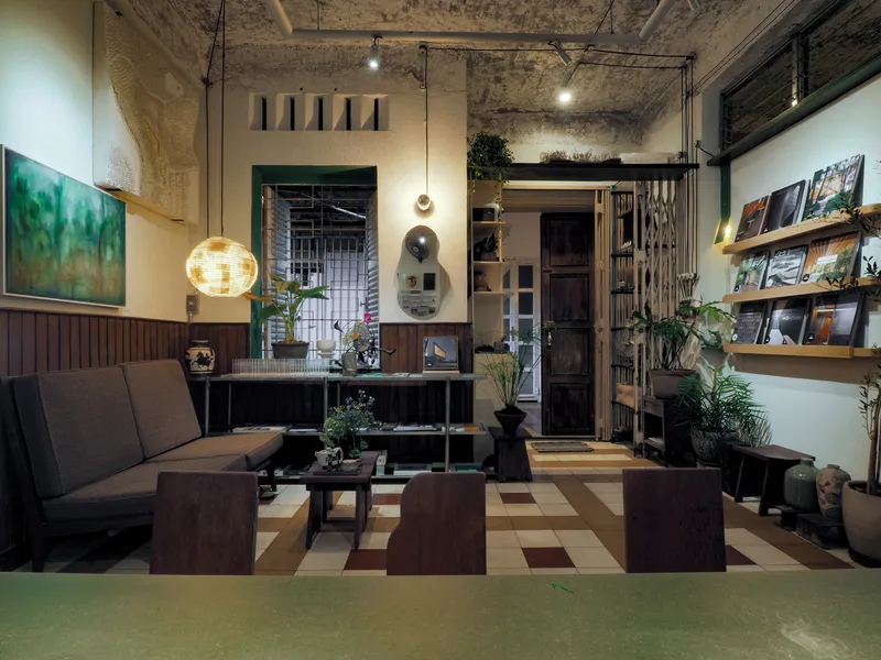 Interior with exposed concrete ceiling, timber wall paneling, and checkered floor tiles illuminated by pendant lights