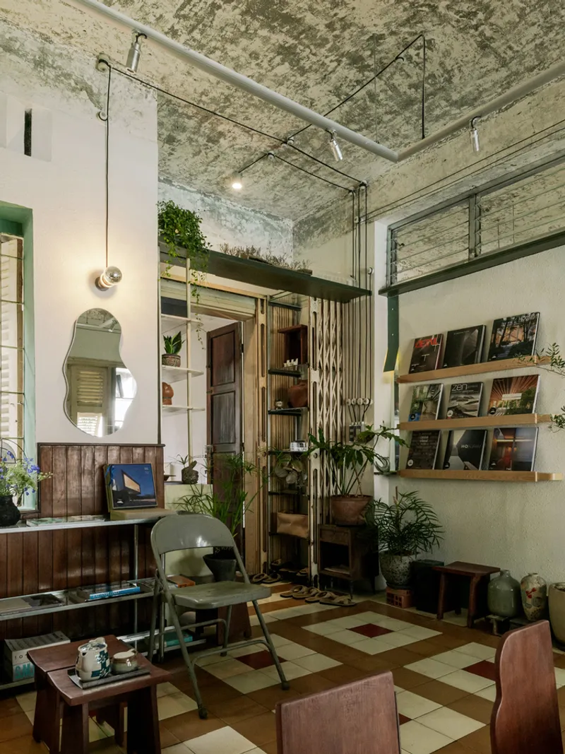 Double-height interior with exposed concrete ceiling, suspended pendant lights, and chequered floor below mezzanine level