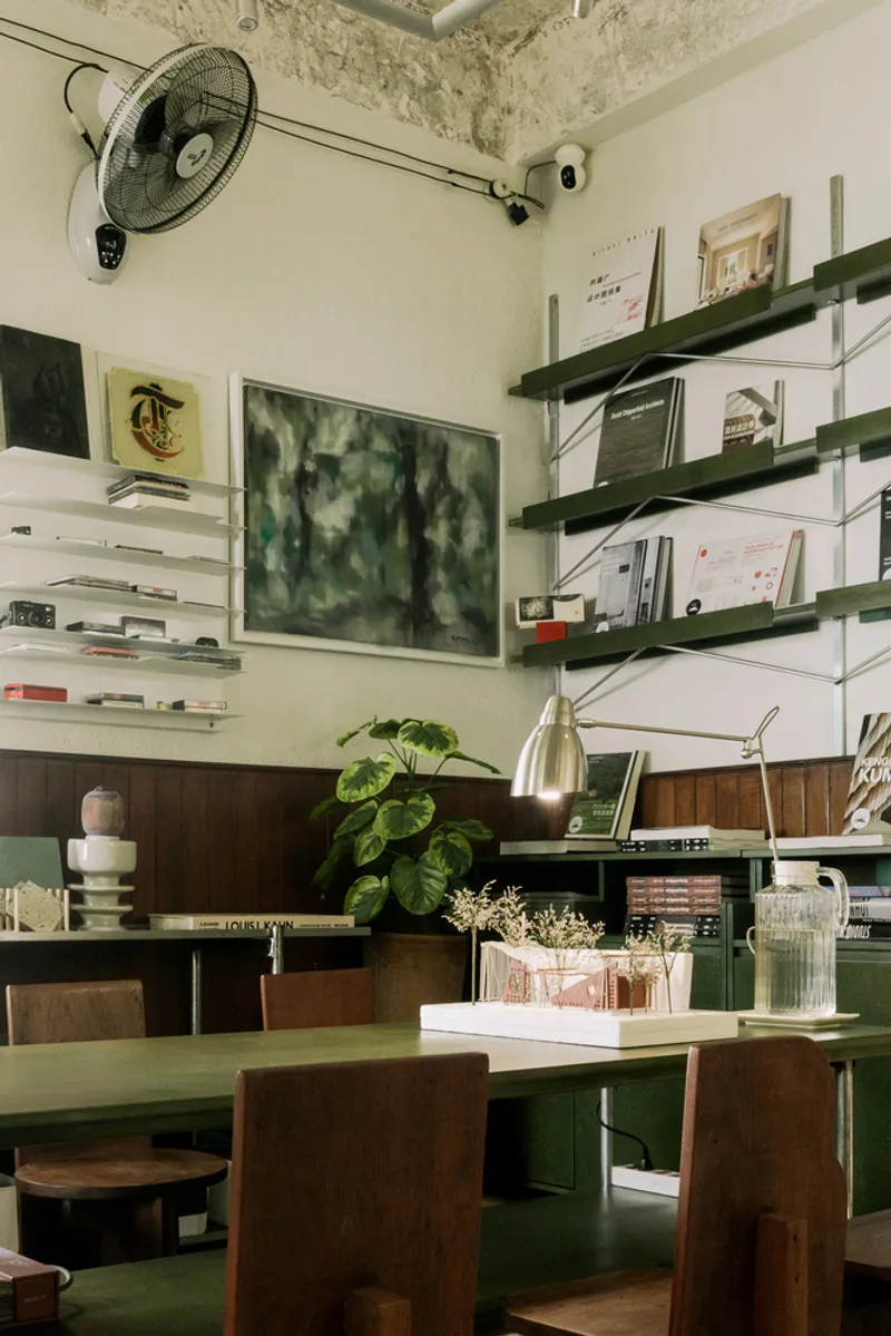 Wall-mounted shelving system in green and timber displaying books and objects beneath a ceiling fan