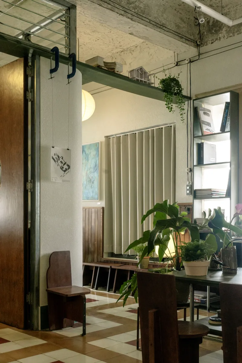 Mezzanine level with green steel beam and hanging plants above a vertical fabric panel and seating area