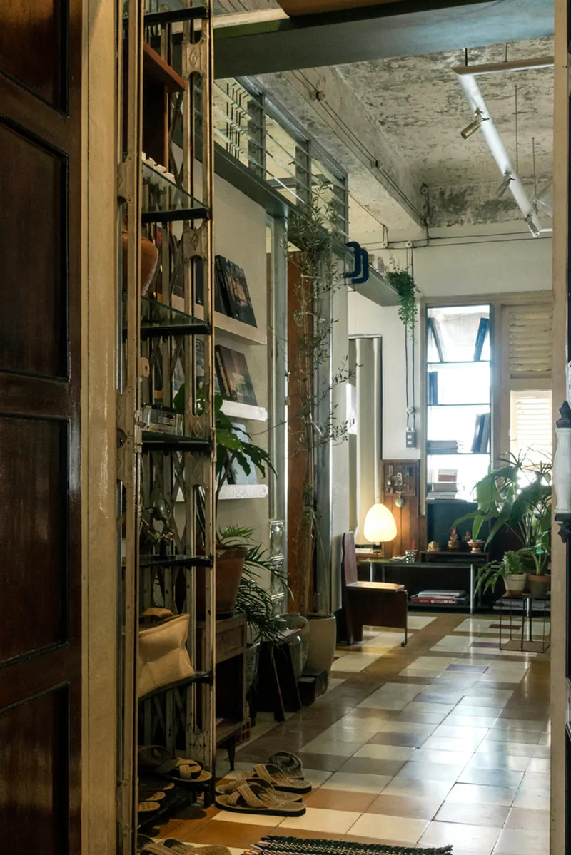 Entry threshold framed by timber door and metal shelving with trailing plants against exposed concrete above