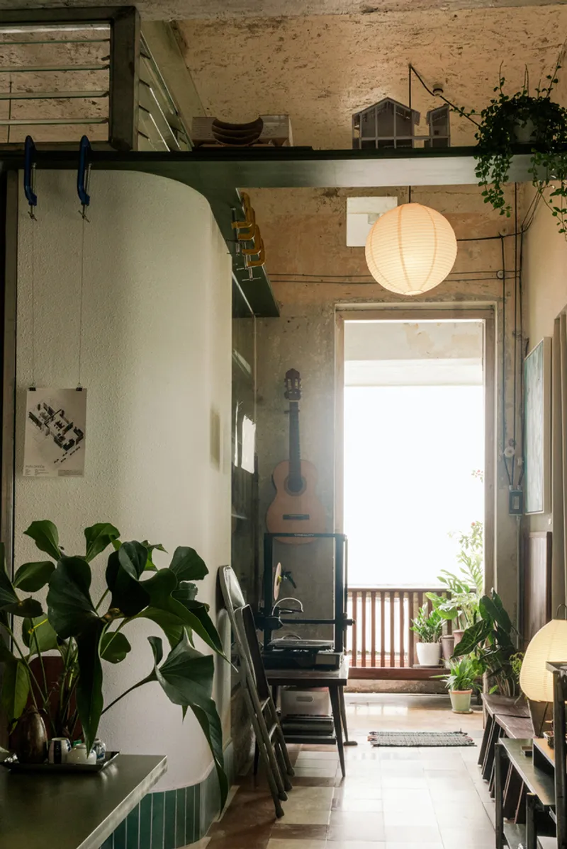 Corridor leading to an open doorway with paper lantern and potted plants framing the threshold