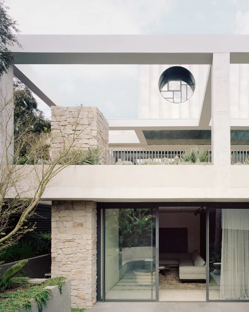 Stacked volumes with circular skylight puncturing cantilevered roof slab above stone-clad walls