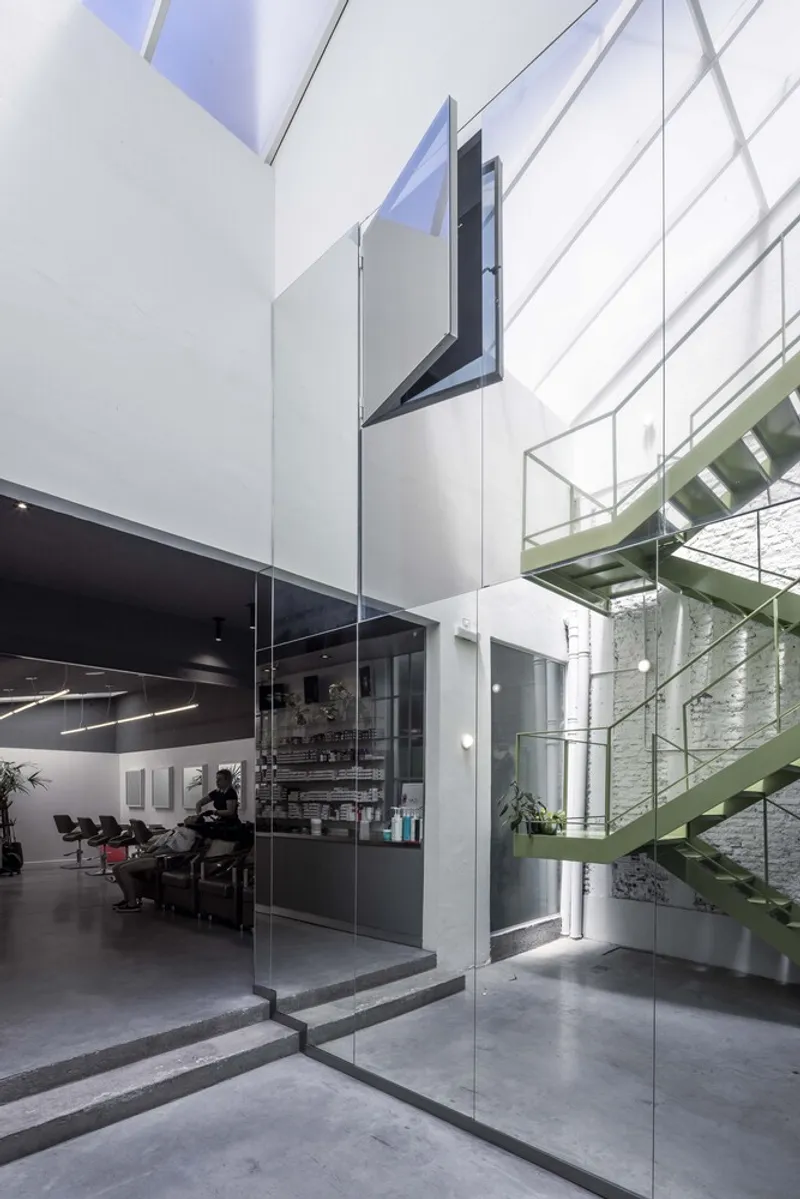 Double-height interior with glass partition, polished concrete floor and open skylight above white walls