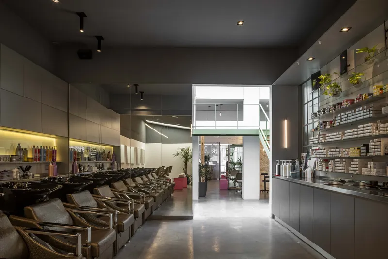 Salon interior with reclined wash chairs and product shelving overlooking a mezzanine level