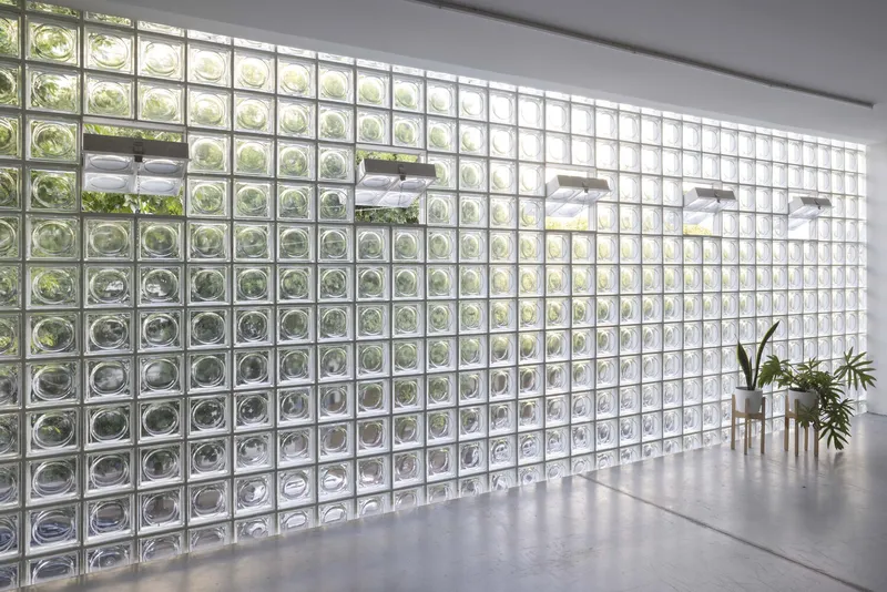 Glass block wall with operable windows and potted plants on a polished concrete floor