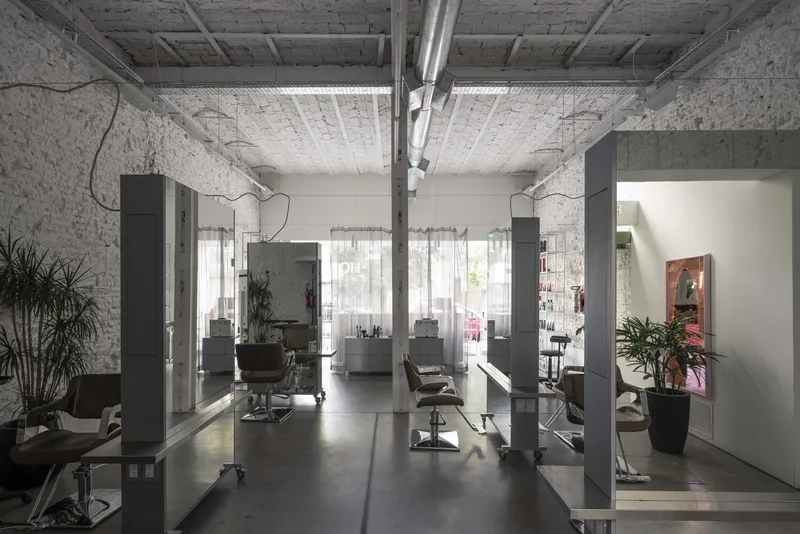 Long interior view of the salon with freestanding glass partitions and natural light from storefront windows