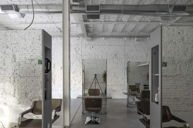 Glass partitioned salon space with exposed white brick walls and exposed ductwork on the ceiling