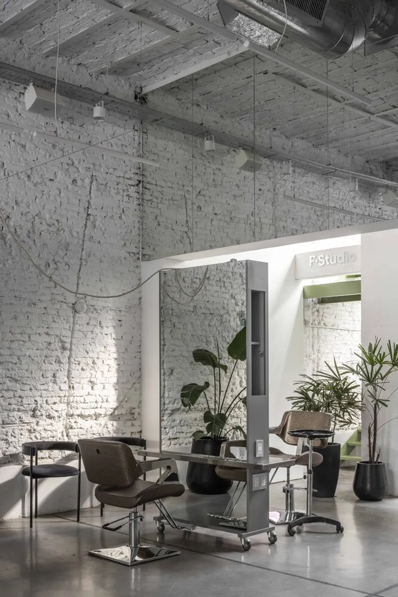 Individual styling station framed by white portal opening with potted plants on polished concrete floor