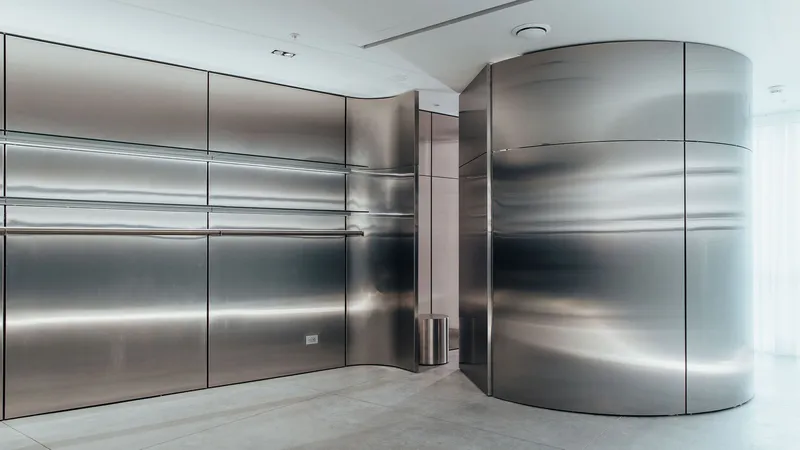 Corner detail of curved stainless steel wall meeting flat panels with horizontal light slots