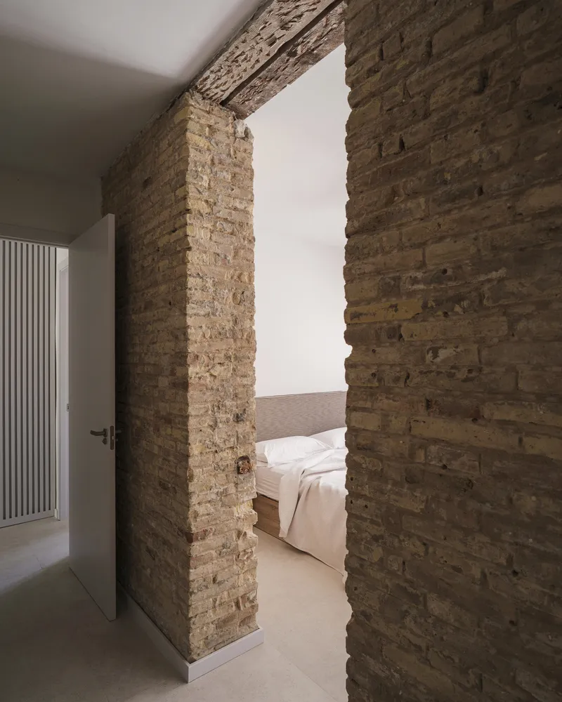 Exposed brick threshold framing a view through to a bedroom with white walls
