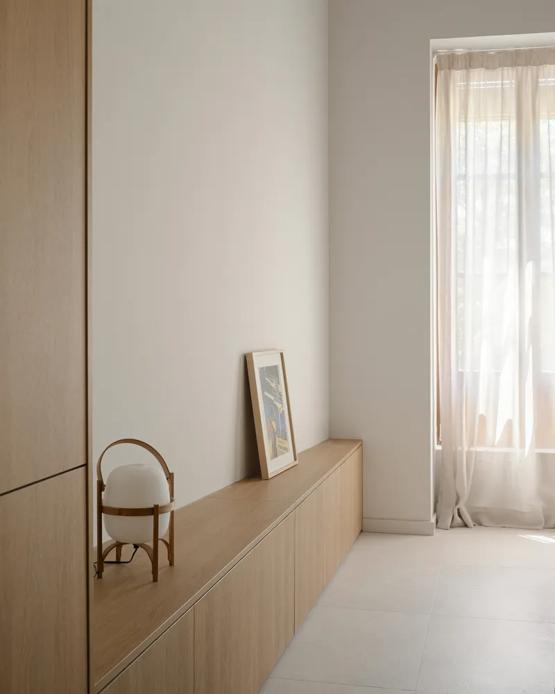 Timber credenza beneath a framed artwork beside a window with sheer curtains