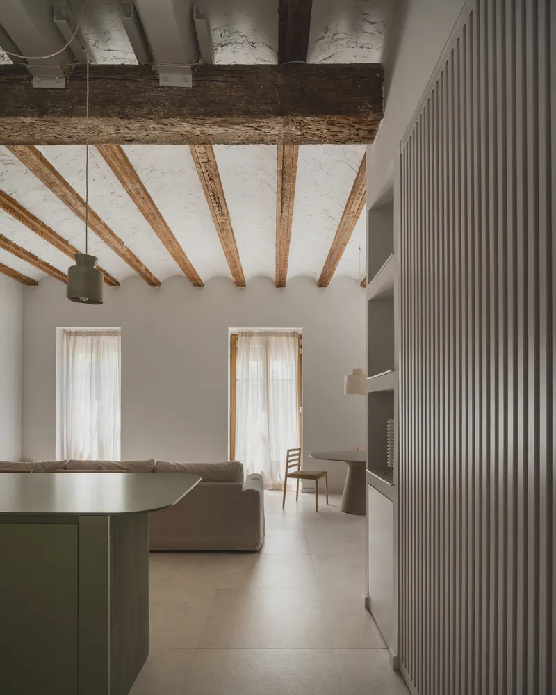 Living area view through vertical timber slats with exposed ceiling beams and sheer curtains in daylight