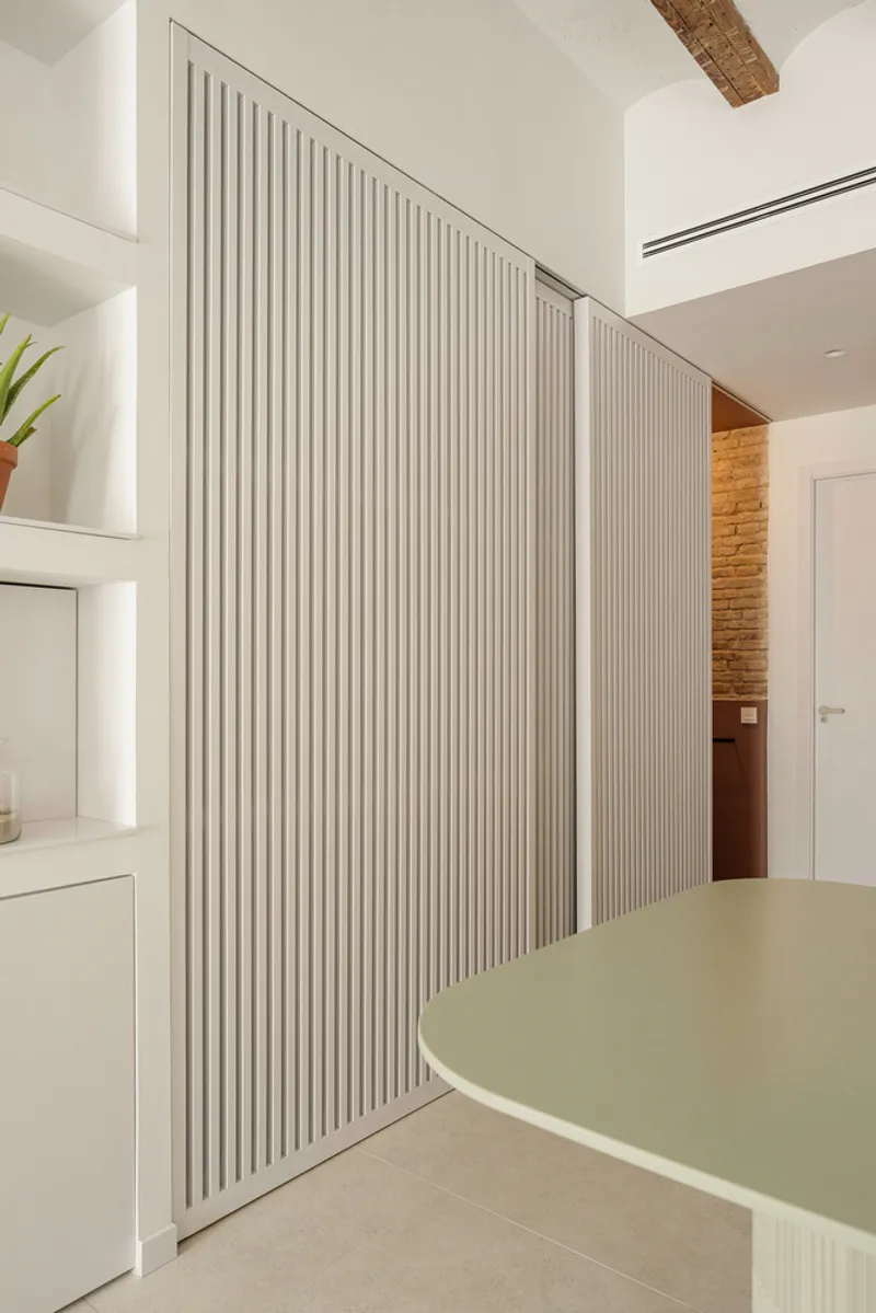 Fluted sliding screen partially open to show timber sauna enclosure beyond kitchen workspace