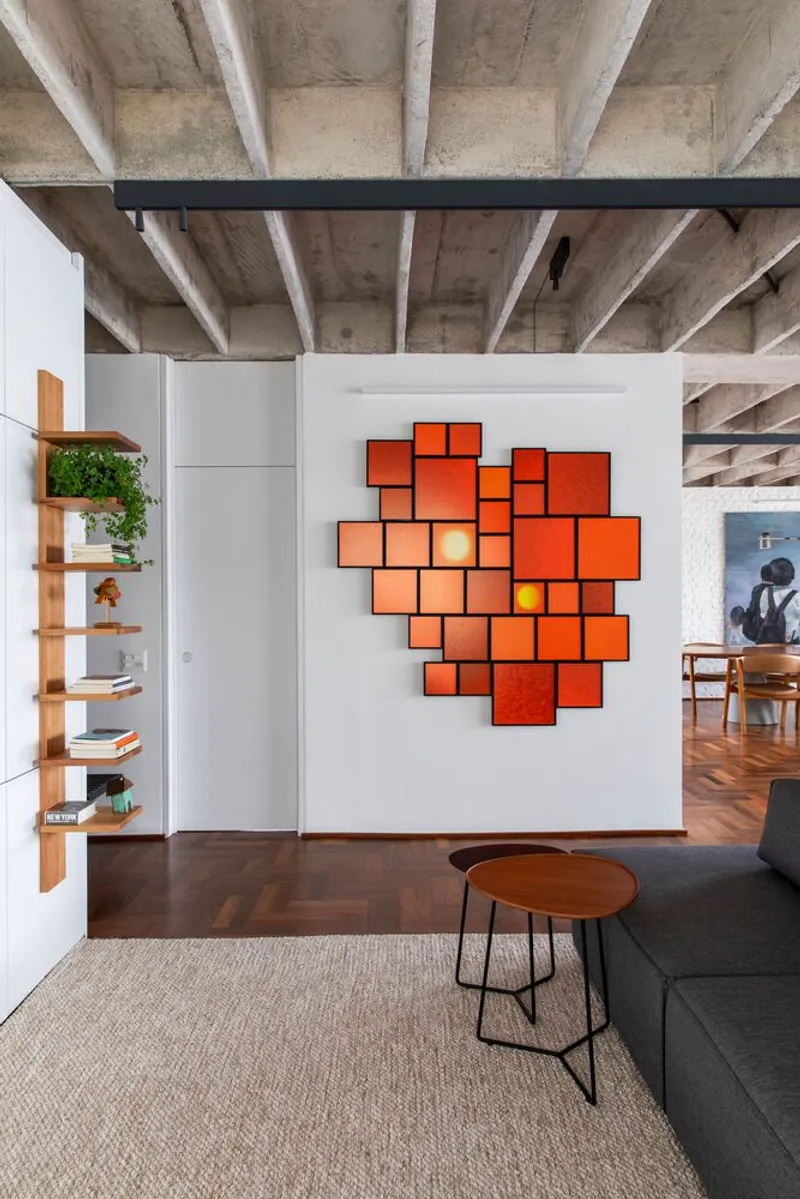 White partition wall with geometric orange panel installation under exposed concrete ceiling beams