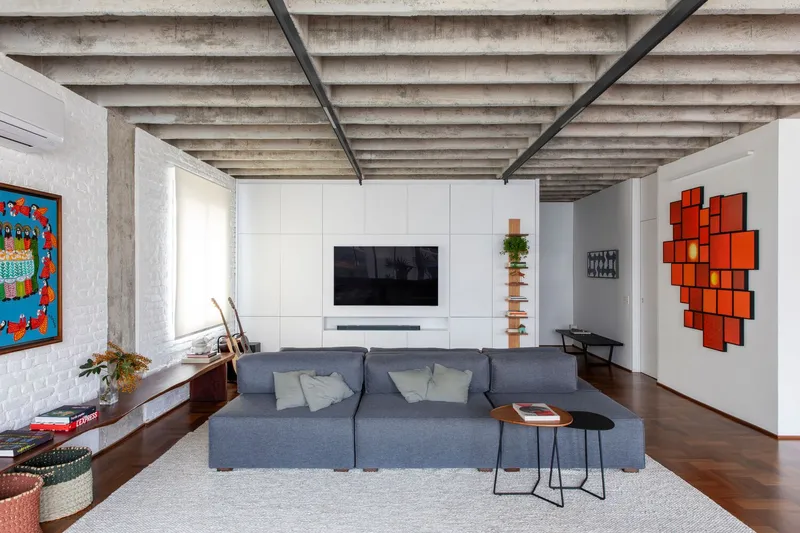 Living room with exposed concrete beam ceiling and orange geometric wall installation