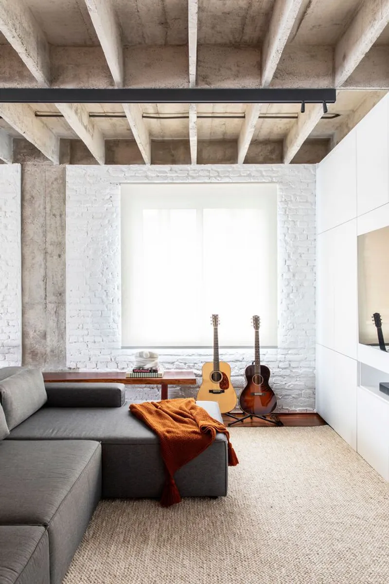 White brick window alcove with concrete beams above and two acoustic guitars on the seating ledge