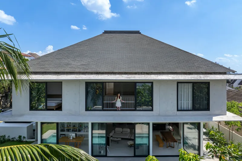 Rear facade showing the pyramidal tiled roof with a figure standing on the upper-level balcony