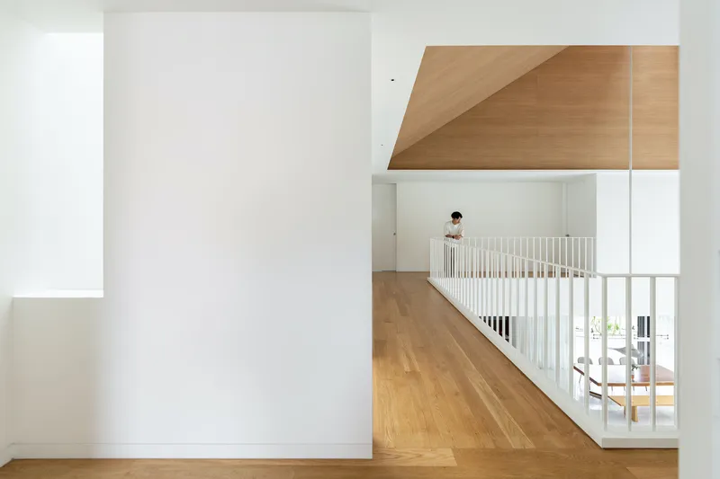 Interior balcony with white slat railing and figure standing beside the upper circulation route