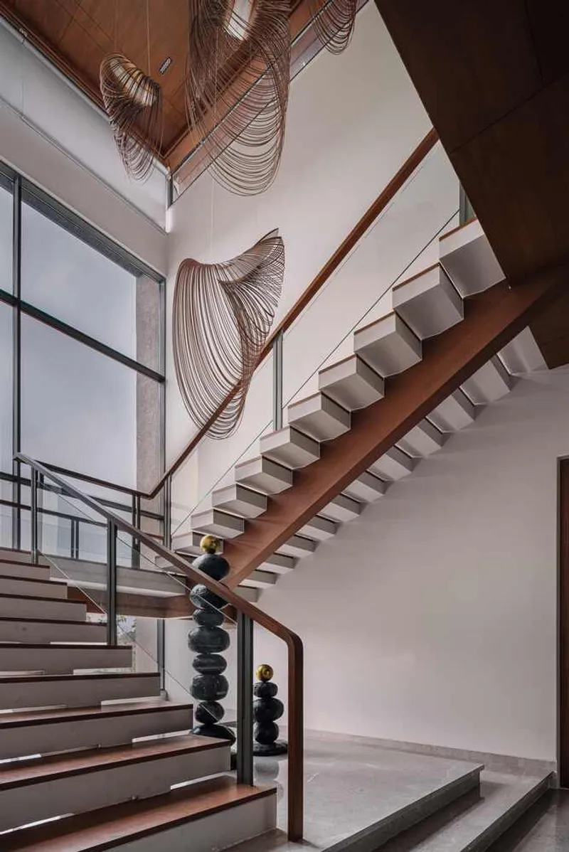 Double-height stairwell with timber treads and sculptural woven pendant lights descending from above