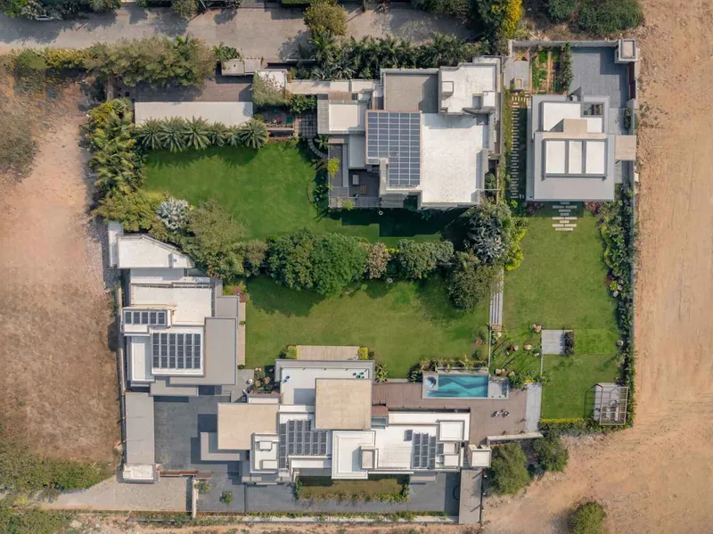 Aerial view of flat roofs with solar panels surrounded by landscaped lawn and a swimming pool