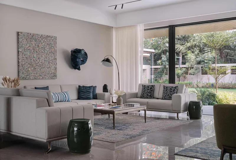 Living room with floor-to-ceiling glazing framing views of the garden and trees beyond