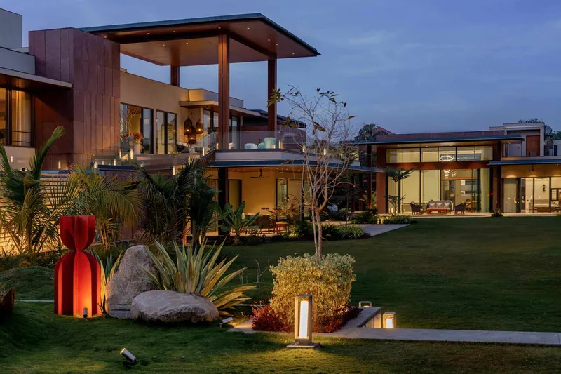 Garden view of the residence at dusk with illuminated volumes and landscape lighting among planted beds