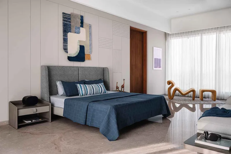 Bedroom with textured wall paneling and sheer curtains diffusing daylight from the window