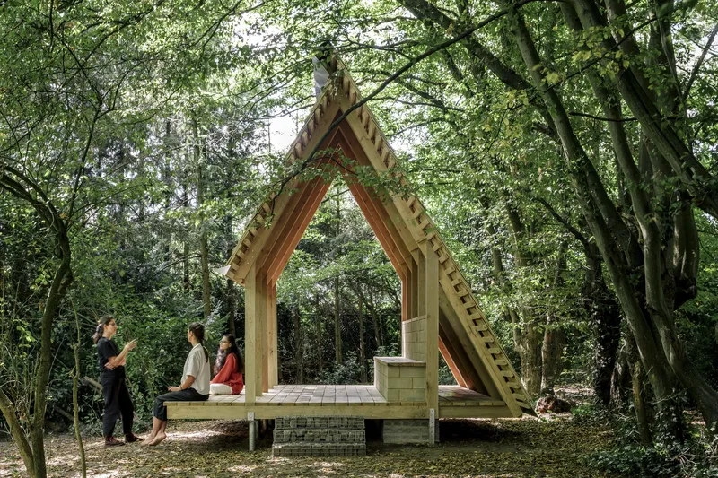 Frontal view of the peaked timber frame pavilion with visitors seated on the raised deck