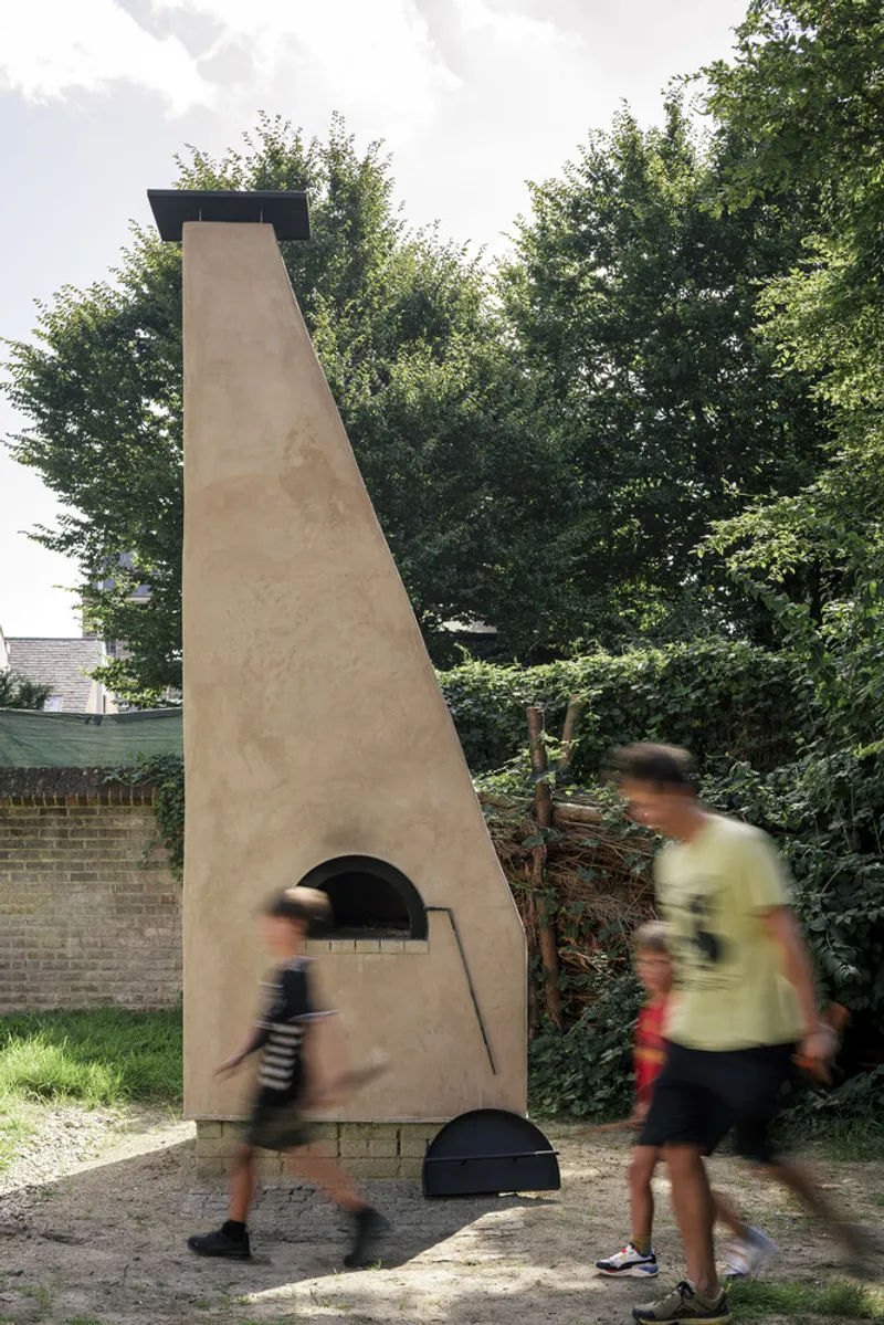 Tapered clay render chimney with two arched openings as visitors walk past in motion blur