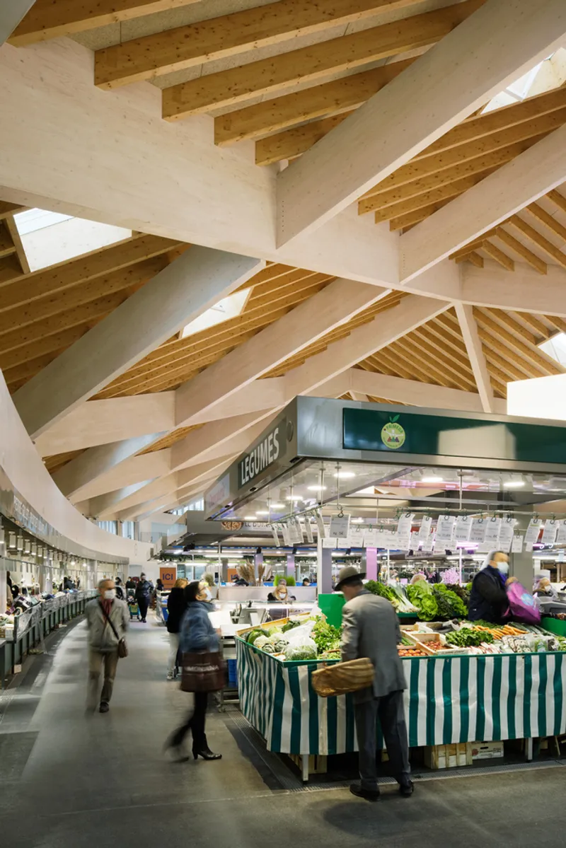 Close-up of the laminated timber roof structure radiating above a produce stand with striped awning