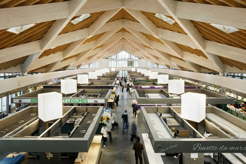 Interior view of the market hall with exposed timber roof trusses above vendor stalls and shoppers