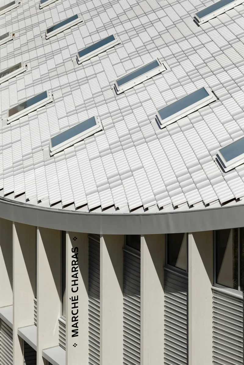 Detail of curved roof edge with horizontal metal tiles and triangular vents above vertical facade louvers