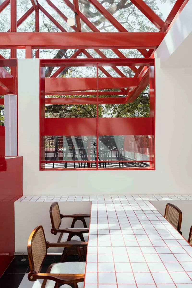 Covered terrace with white tile floor and timber cane chairs beneath red steel truss canopy