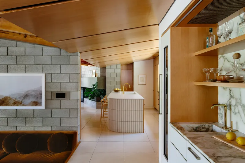 Open kitchen and living area with fluted wood ceiling and concrete block fireplace wall