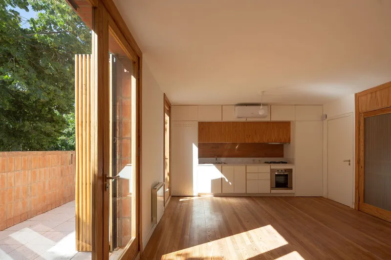 Open plan kitchen and living space with timber flooring and vertical timber battens at the glazed doors