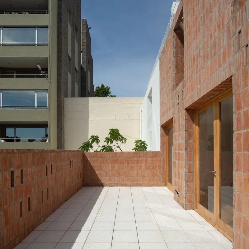 Terrace with pale stone pavers and perforated brick parapet walls under clear blue sky