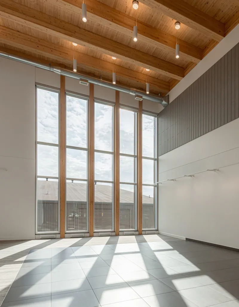 Floor-to-ceiling window wall with vertical timber mullions and exposed wood plank ceiling in daylight