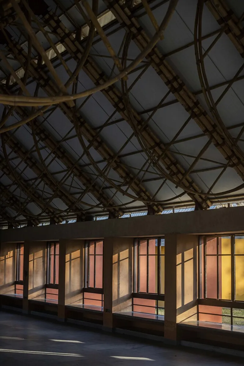 Interior view of bamboo lattice dome structure above a corridor with colorful translucent window panels
