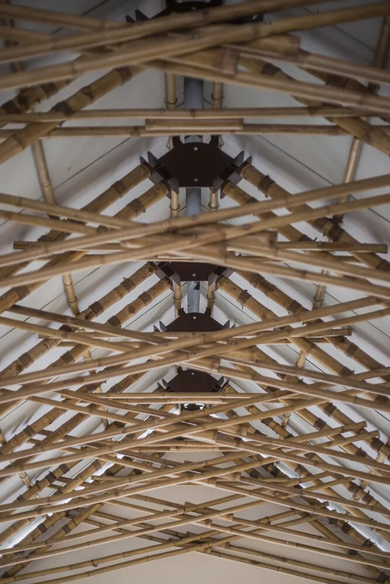 Upward view of the bamboo truss structure with repeating hexagonal nodes and metal junction plates